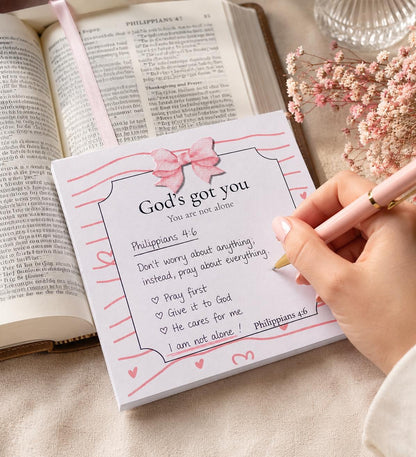 God's Got You Bible verse notepad styled beside an open Bible and pink pen