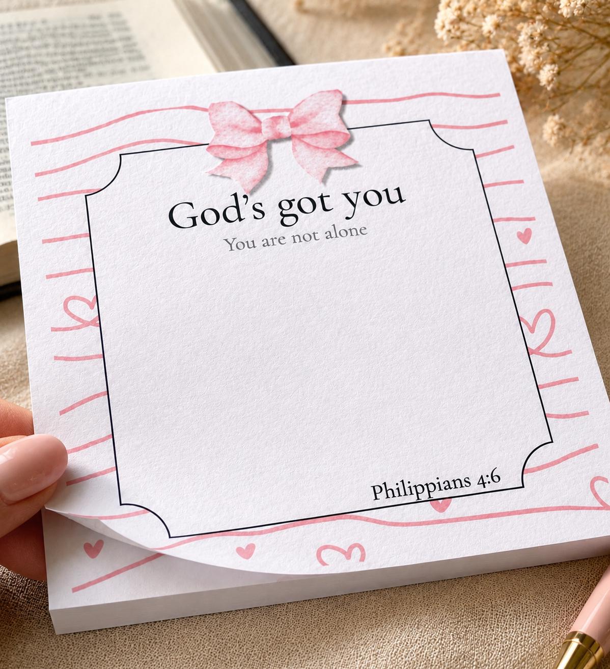 Close-up of God's Got You Christian notepad with pink bow and heart design
